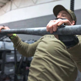 Person performing pull-ups with bear komplex hand grips on a bar in an indoor setting