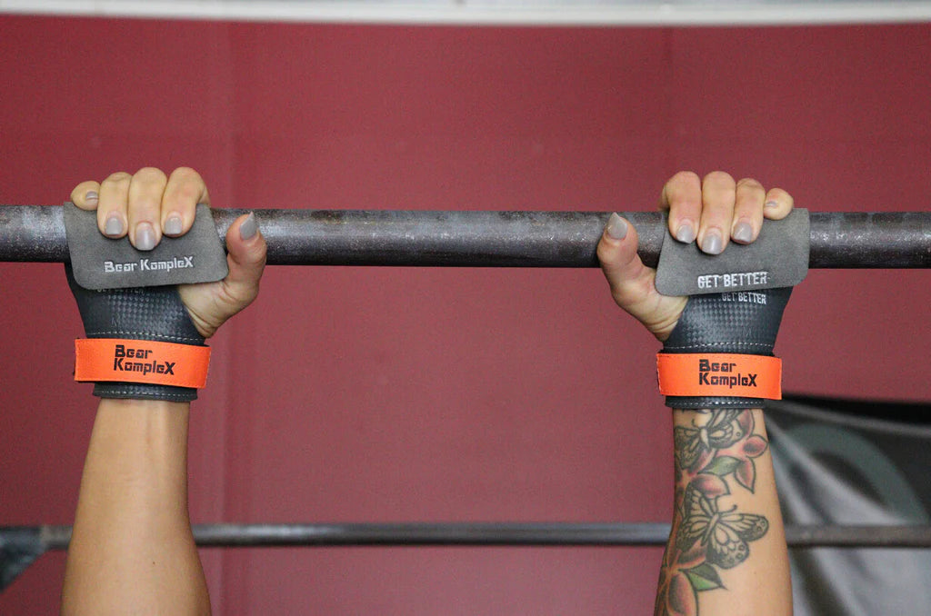Person holding a barbell with Bear Komplex wrist wraps on a red background