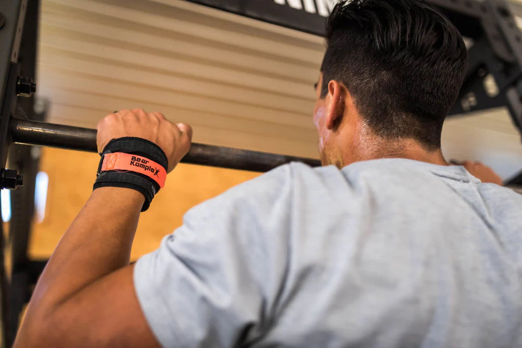 Person exercising with a barbell using bear komplex hand grips in a gym setting