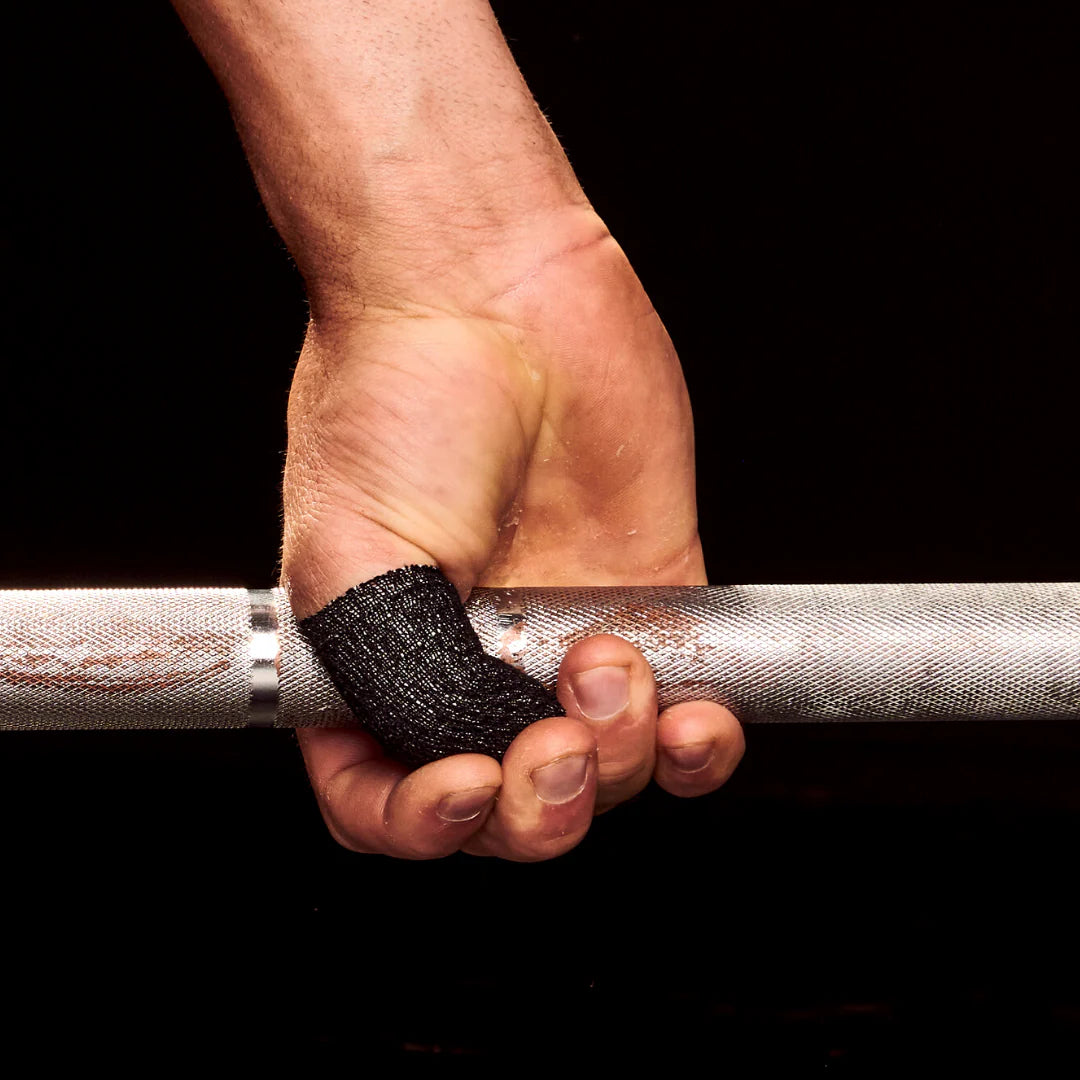 Hand holding a barbell with black frog grip thumb tape on a black background