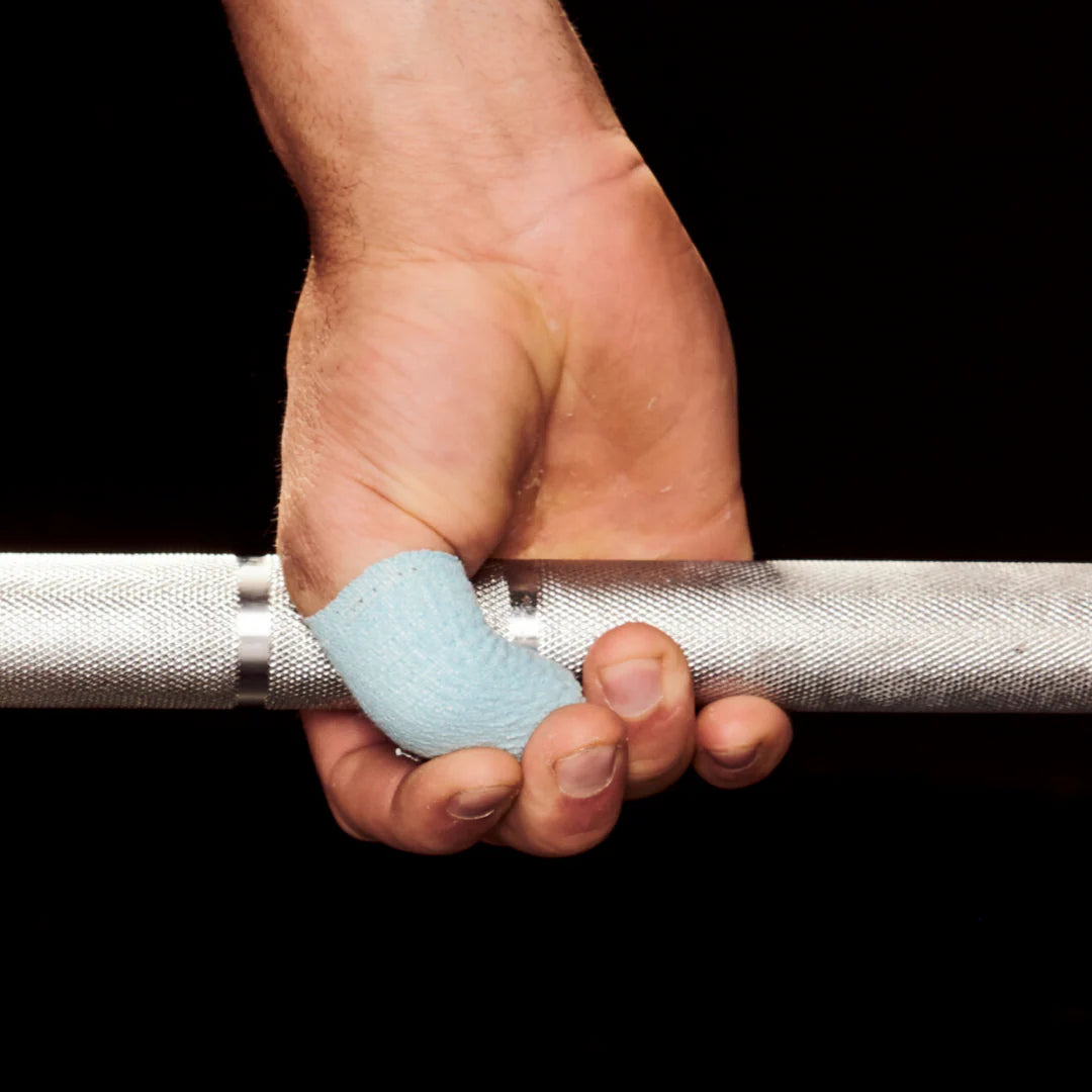 Hand holding a barbell with blue frog grip thumb tape on a black background