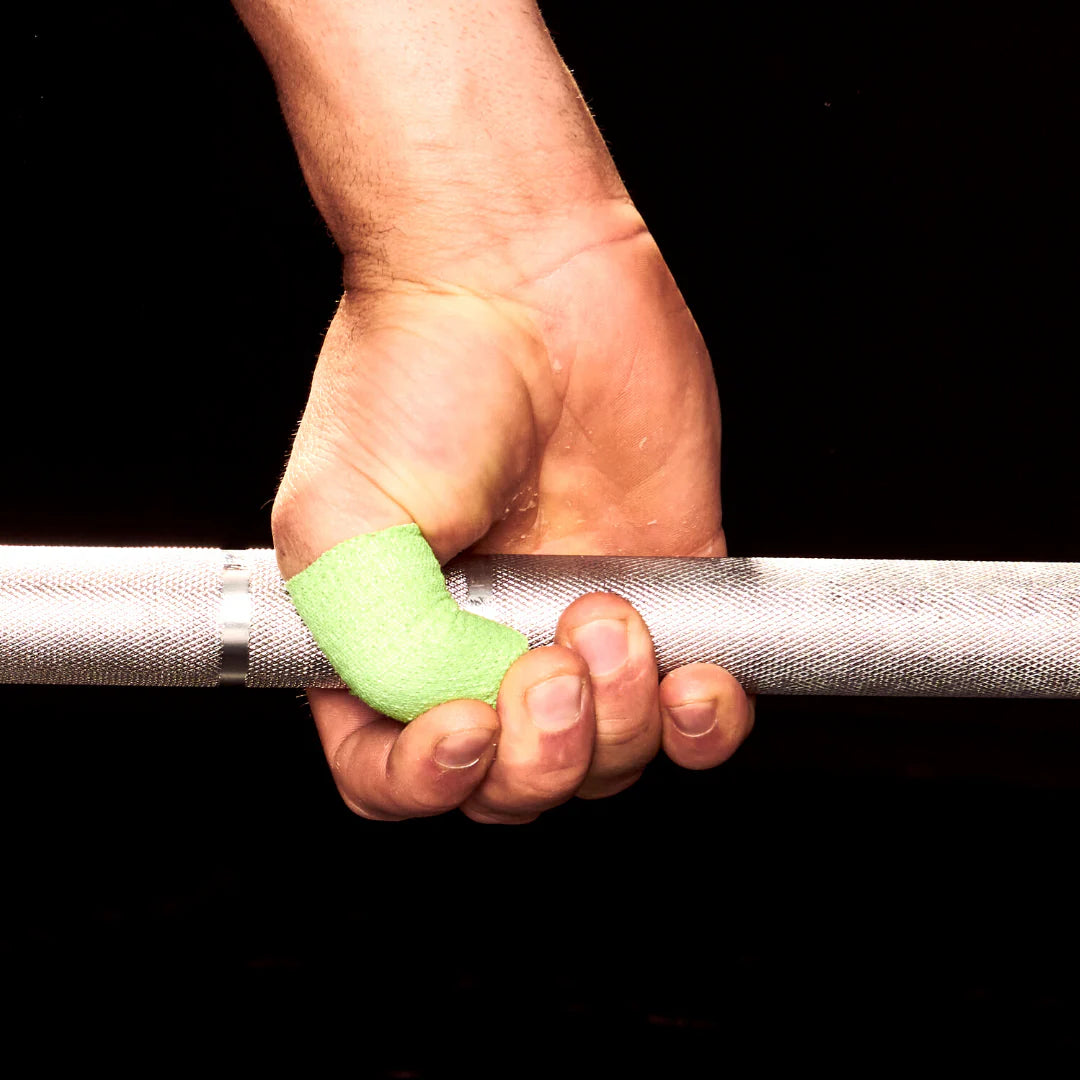 Hand holding a barbell with green frog grip thumb tape on a black background