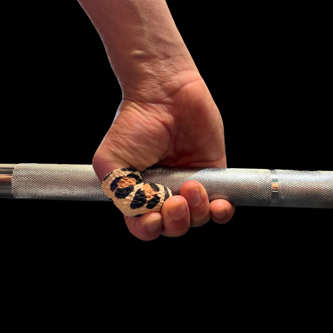 Hand holding a barbell with leopard frog grip thumb tape on a black background
