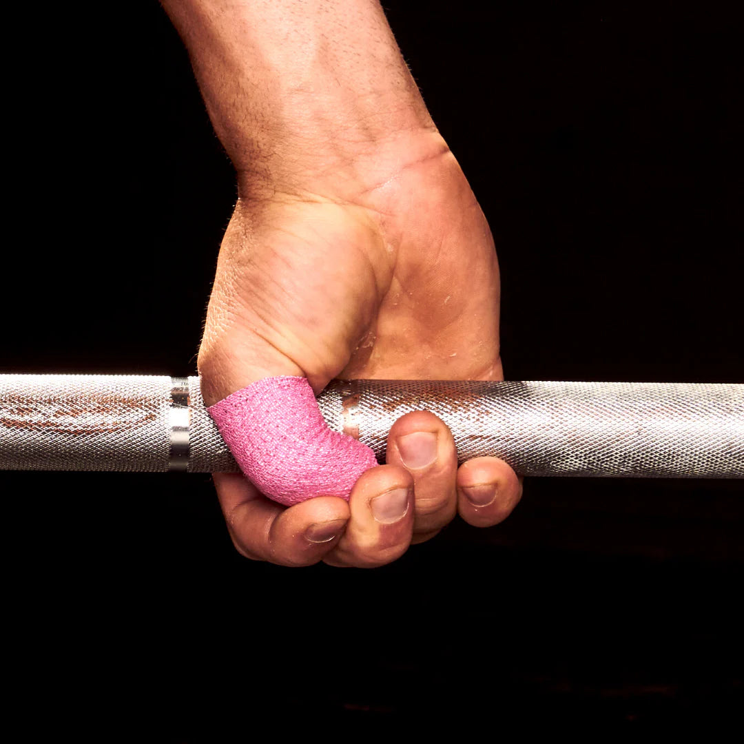 Hand holding a barbell with pink frog grip thumb tape on a black background