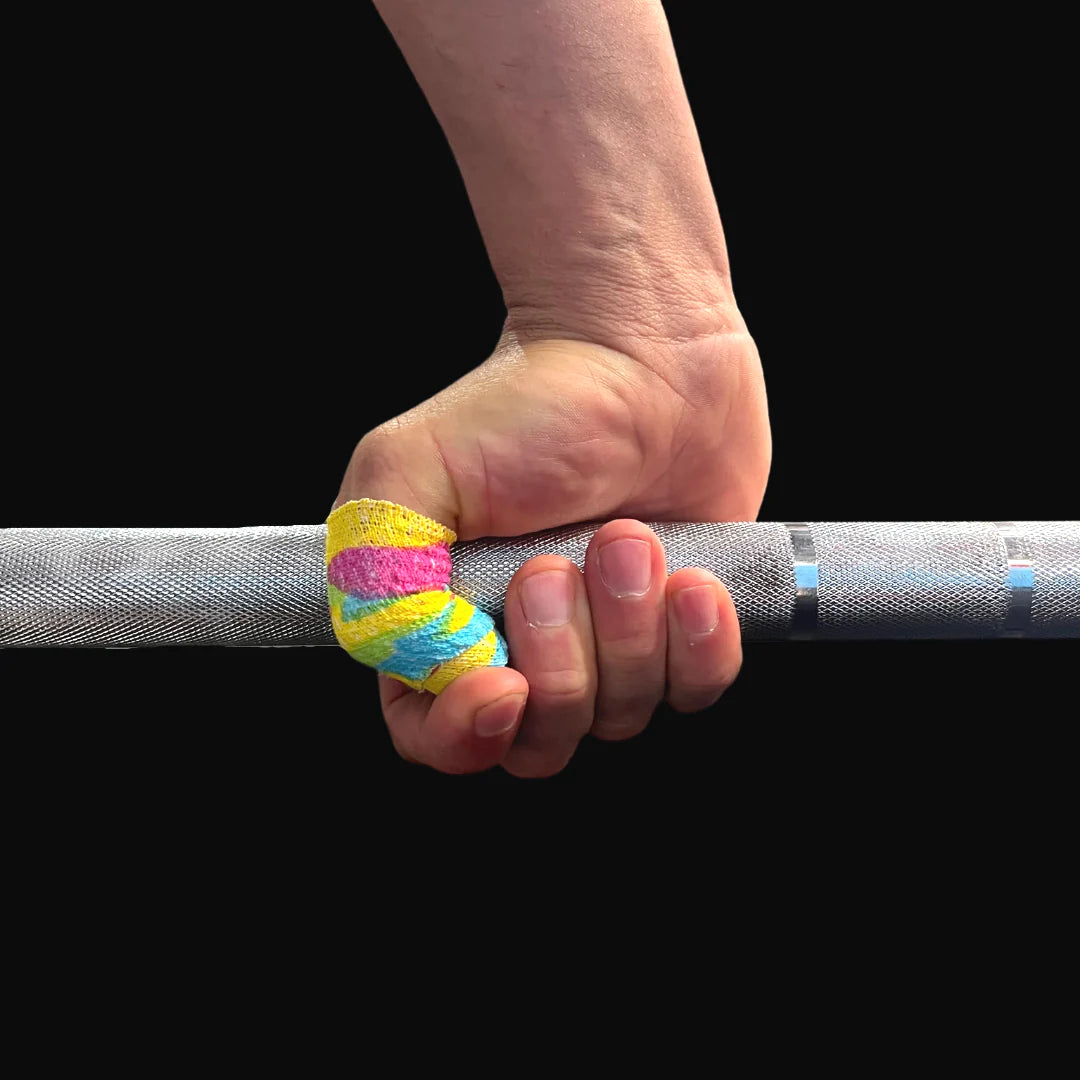 Hand holding a barbell with rainbow frog grip thumb tape on a black background