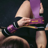 Person using a purple resistance band labeled 'Velites' on a dark background