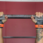 Person holding a barbell with Bear Komplex wrist wraps on a red background