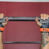 Person holding a barbell with Bear Komplex wrist wraps on a red background