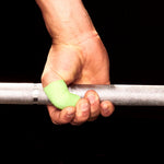 Hand holding a barbell with green frog grip thumb tape on a black background