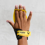Hand wearing a yellow wrist support with 'Victory' branding on a light gray background