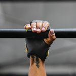 Hand wearing a victory crossfit hand grip gripping a bar against a gray background