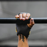 Hand wearing a victory crossfit hand grip gripping a bar against a gray background