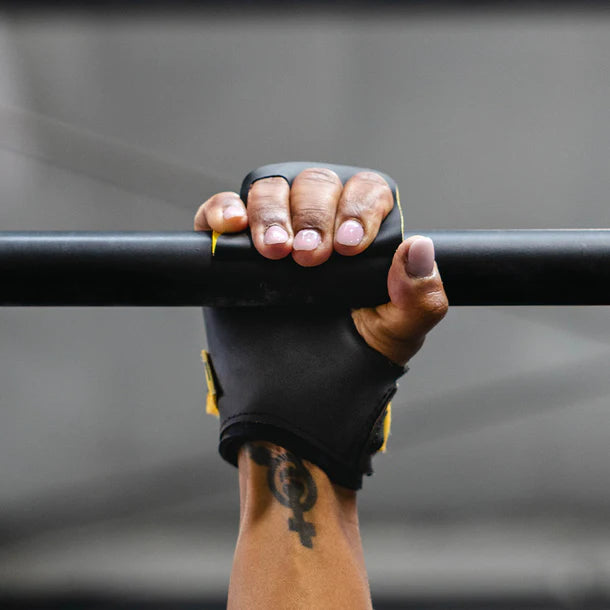 Hand wearing a victory crossfit hand grip gripping a bar against a gray background