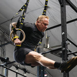 Man exercising victory hand grips using TRX rings in a gym setting