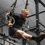 Man exercising victory hand grips using TRX rings in a gym setting