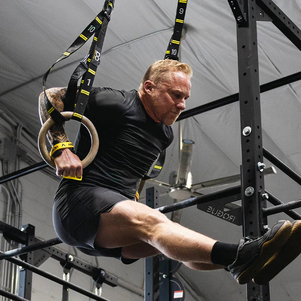 Man exercising victory hand grips using TRX rings in a gym setting