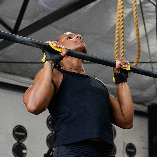 Person performing pull-ups on a bar with a gym background using victory grips