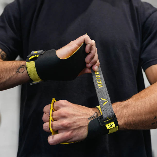 Person wearing black and yellow wrist wraps with 'VICTORY' branding.