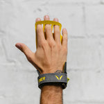 Hand wearing a yellow and gray Victory wrist hand grips on a light gray background