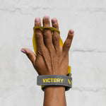 Hand wearing a yellow wrist wrap with 'Victory' branding on a light gray background