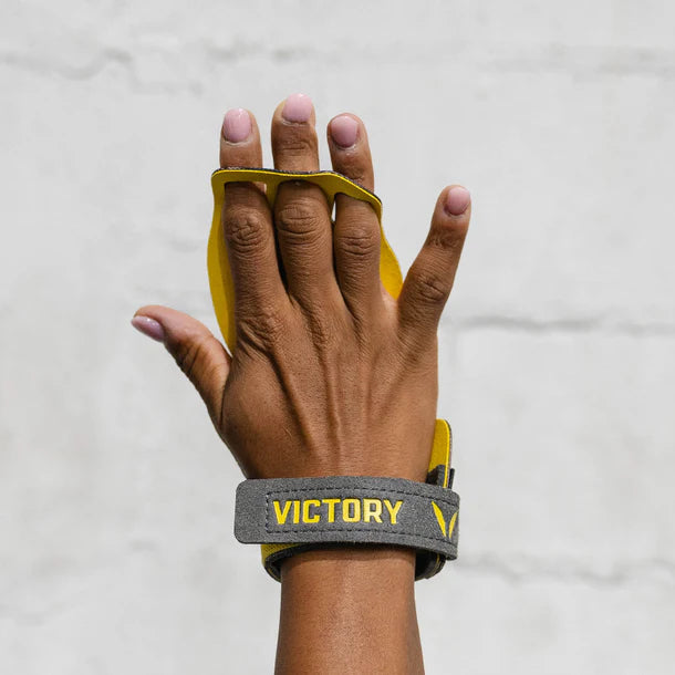 Hand wearing a yellow wrist wrap with 'Victory' branding on a light gray background