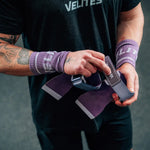 CrossFit athlete strapping on purple Velites All Terrain gymnastic grips before a workout