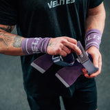 CrossFit athlete strapping on purple Velites All Terrain gymnastic grips before a workout