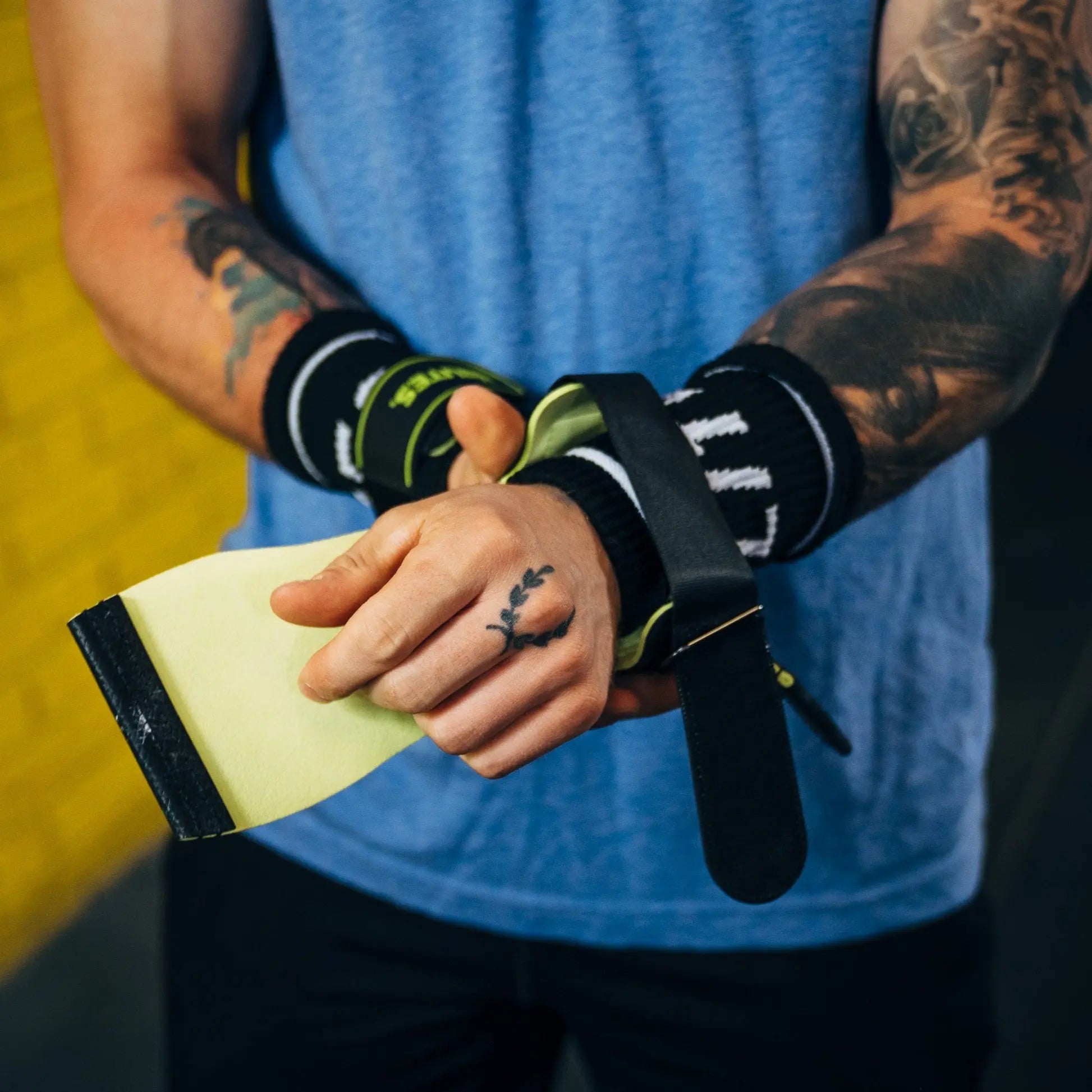 CrossFit athlete strapping on black and yellow Velites Quad Ultra no chalk gymnastic grips before workout
