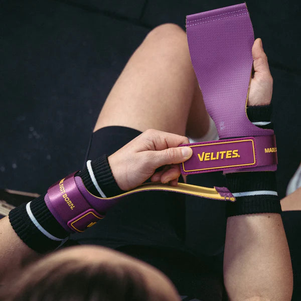 CrossFit athlete putting on purple and mustard Velites Quad Ultra no chalk gymnastic grips before bar workout