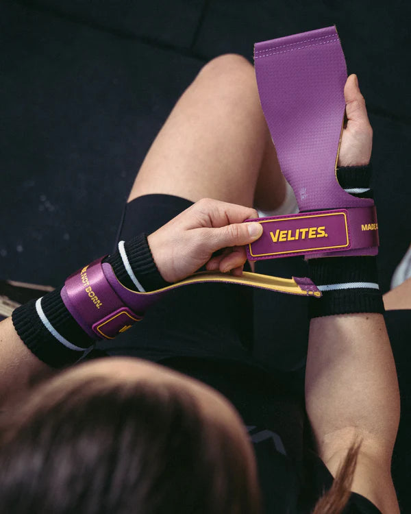 CrossFit athlete putting on purple and mustard Velites Quad Ultra no chalk gymnastic grips before bar workout
